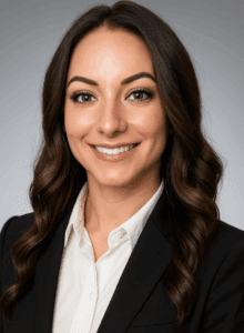 Professional woman with dark hair in business attire smiling.