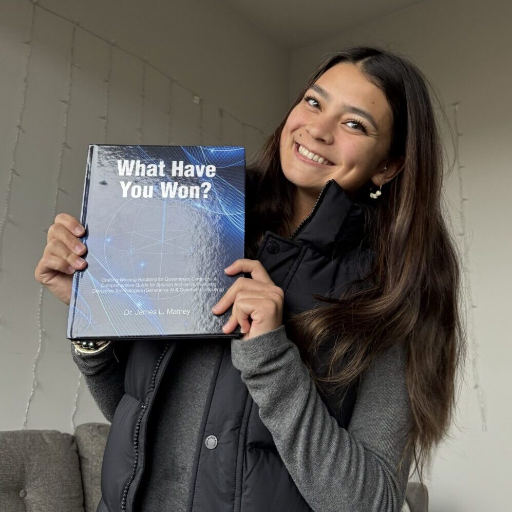 A smiling woman holding a book titled 'What Have You Won?'.